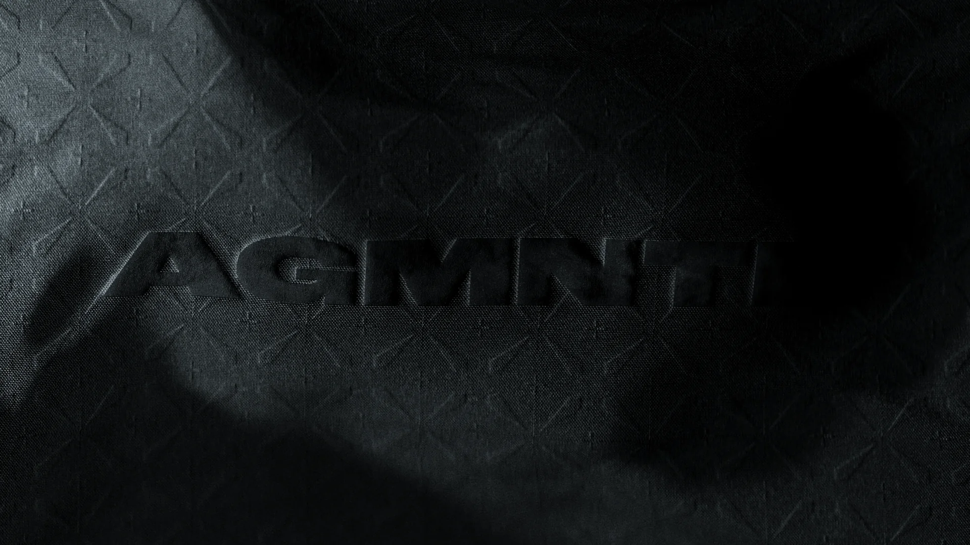 AGMNTD logo embossed on black quilted fabric, Augmented brand identity